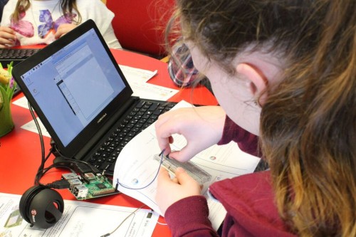 ילדה שעושה פרויקט מחשוב פיזי עם חומרה של Raspberry Pi.