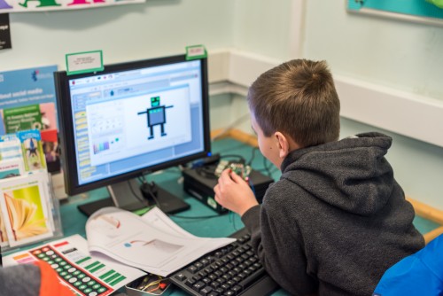 A child codes at a desktop computer.