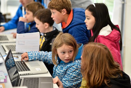 Photo: children concentrate intently on coding activities at a CoderDojo event