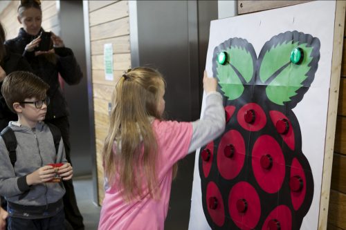 A girl plays a button reaction game at a Raspberry Pi event