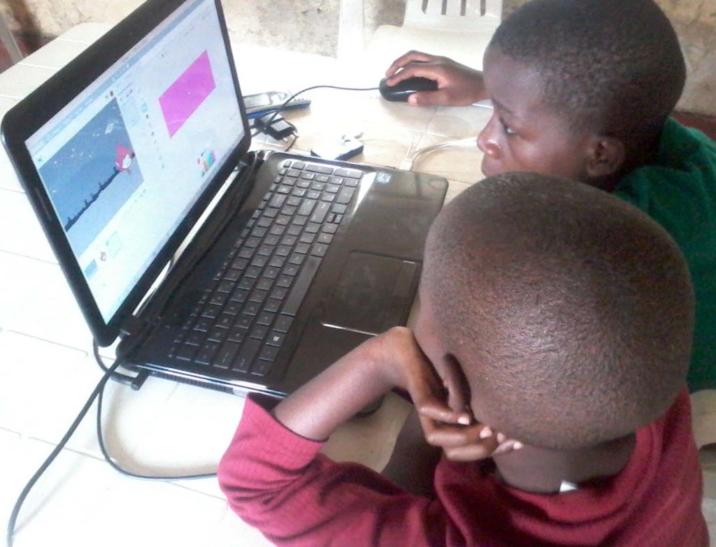 Two young children code in Scratch on a laptop.