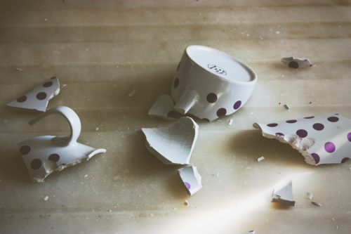 A ceramic mug, broken into several pieces on the floor