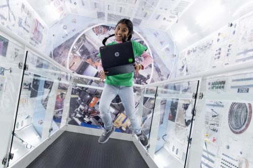 A girl with a laptop in a space station replica.