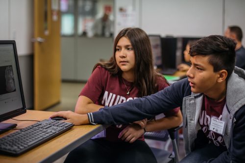 two young people coding at a computer