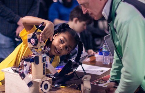 A girl shows off a robot she has built