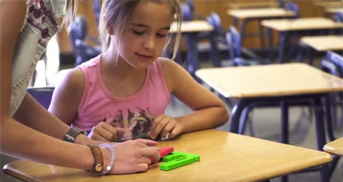 A girl playing with hands-on coding blocks at a desk