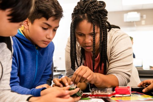 An educator helps two learners set up a Raspberry Pi computer.