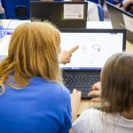 Woman teacher and female student at a laptop