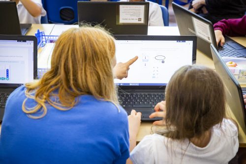 Woman teacher and female student at a laptop.