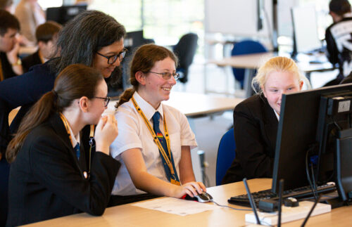 Woman teacher and female students at a computer.