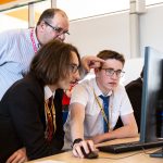 Male teacher and male students at a computer