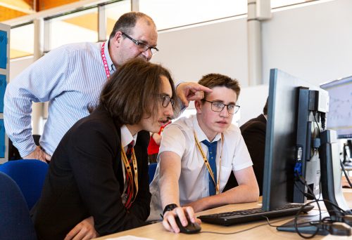 Male teacher and male students at a computer