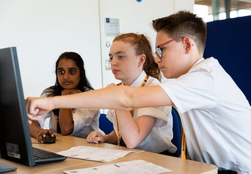 One male and two female teenagers at a computer