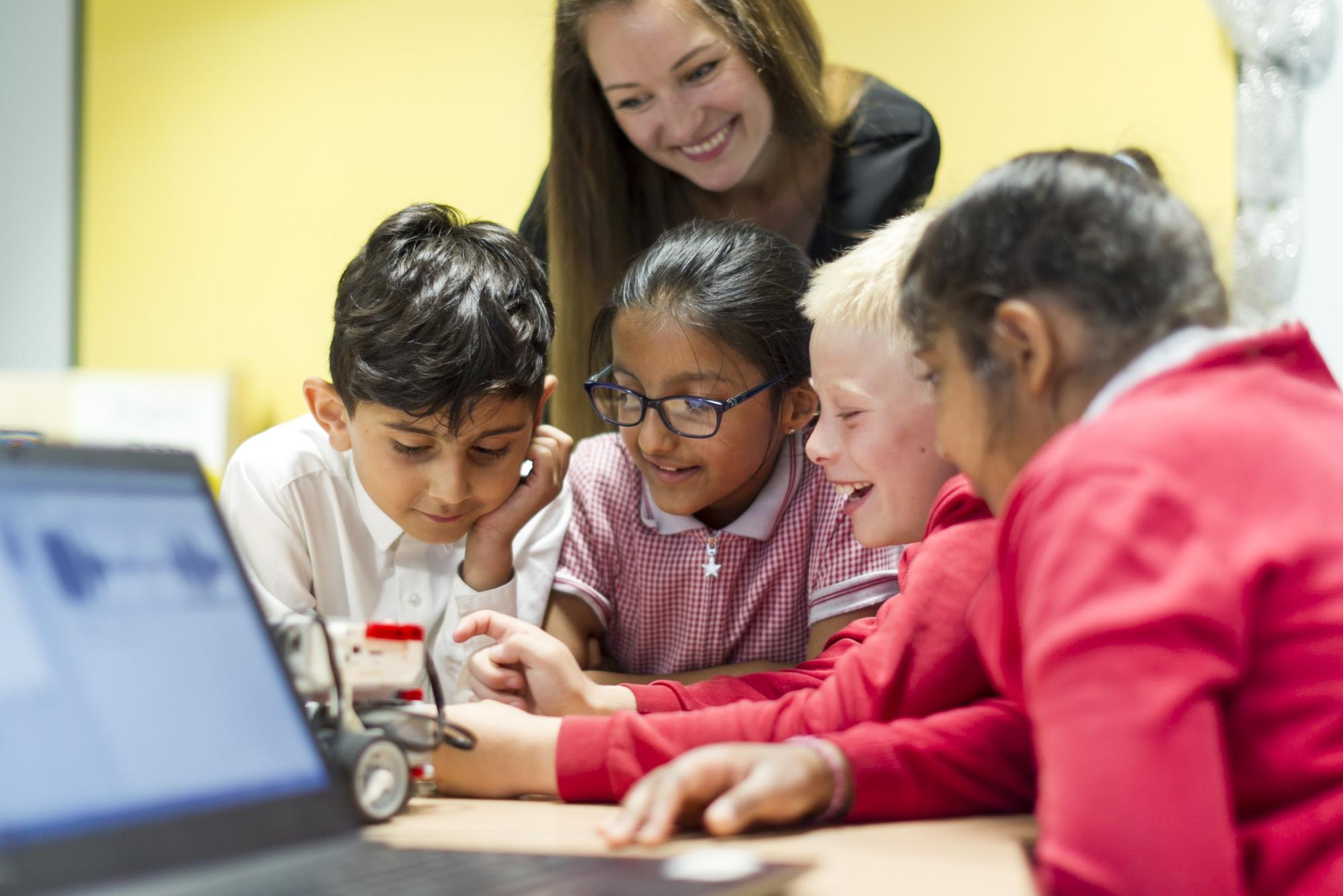 Woman teacher and young students at a computer