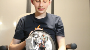 El inventor del reloj lo sostiene con la parte posterior mirando hacia la cámara para mostrarnos cómo funciona y lo mira.