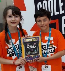 A girl and a boy holding up a book about coding