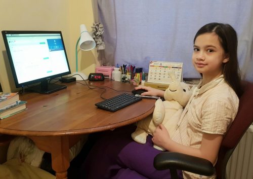 A young girl sitting at a desk using a Raspberry Pi computer