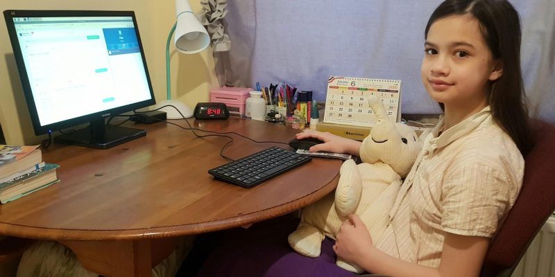 A young girl sitting at a desk using a Raspberry Pi computer