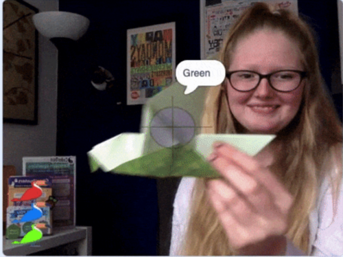 Photo of a young woman holding an origami bird up to the camera