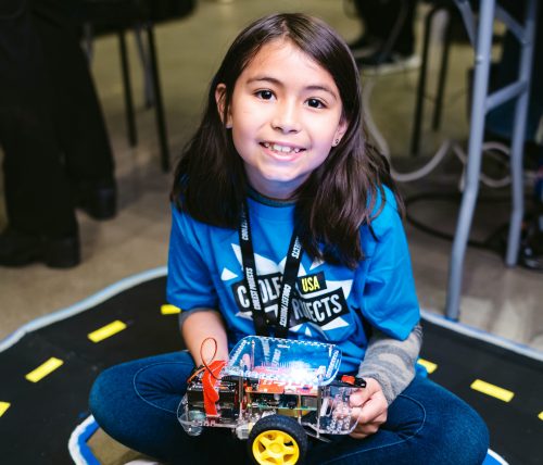 A smiling girl holding a robot buggy in her lap