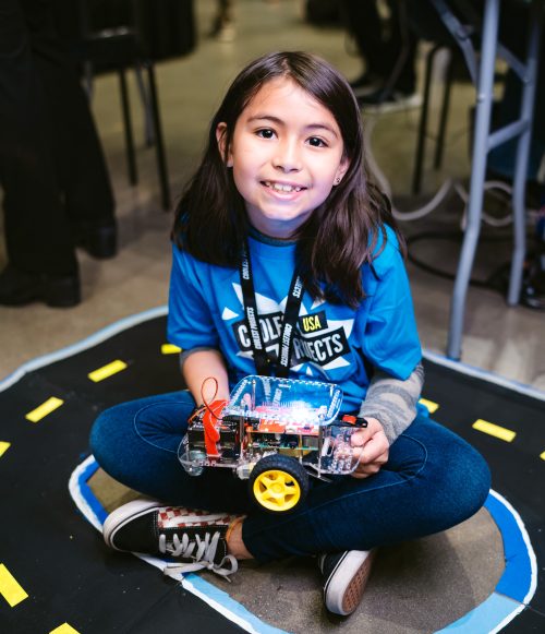 A smiling girl holding a robot buggy in her lap