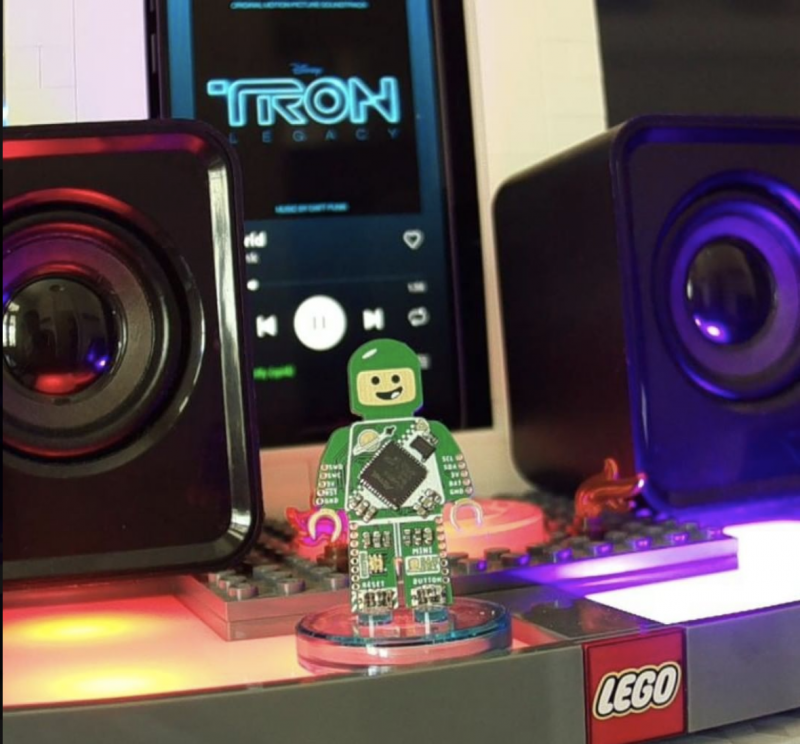 A Tron mini figure on the reader with the Tron movie soundtrack seen playing on the screen behind it