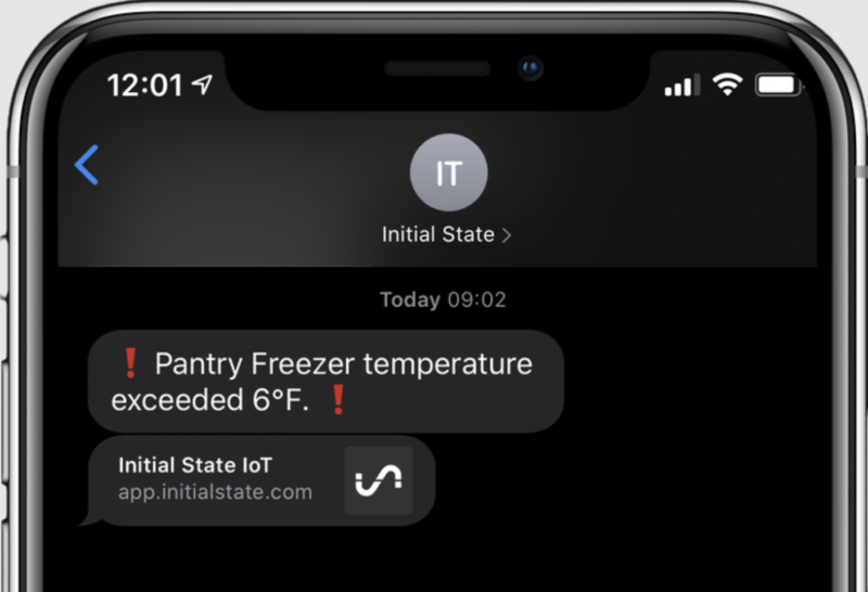 A phone screen showing a text alert that a freezer temperature has gone too high