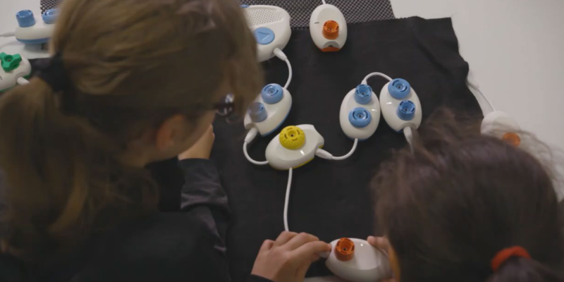 Two children use a physical computing tool to create a program.