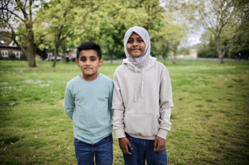 A girl and boy standing on the grass in a park