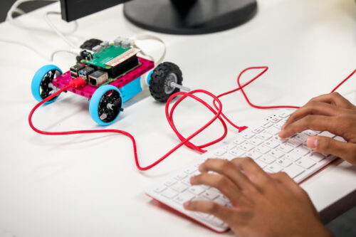 A young person programs a robot buggy built with LEGO bricks and the Raspberry Pi Build HAT.