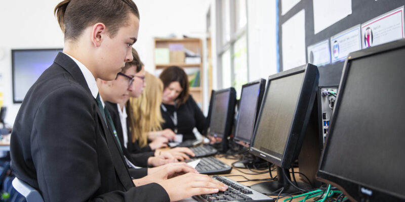 a teenage boy does coding during a computer science lesson.