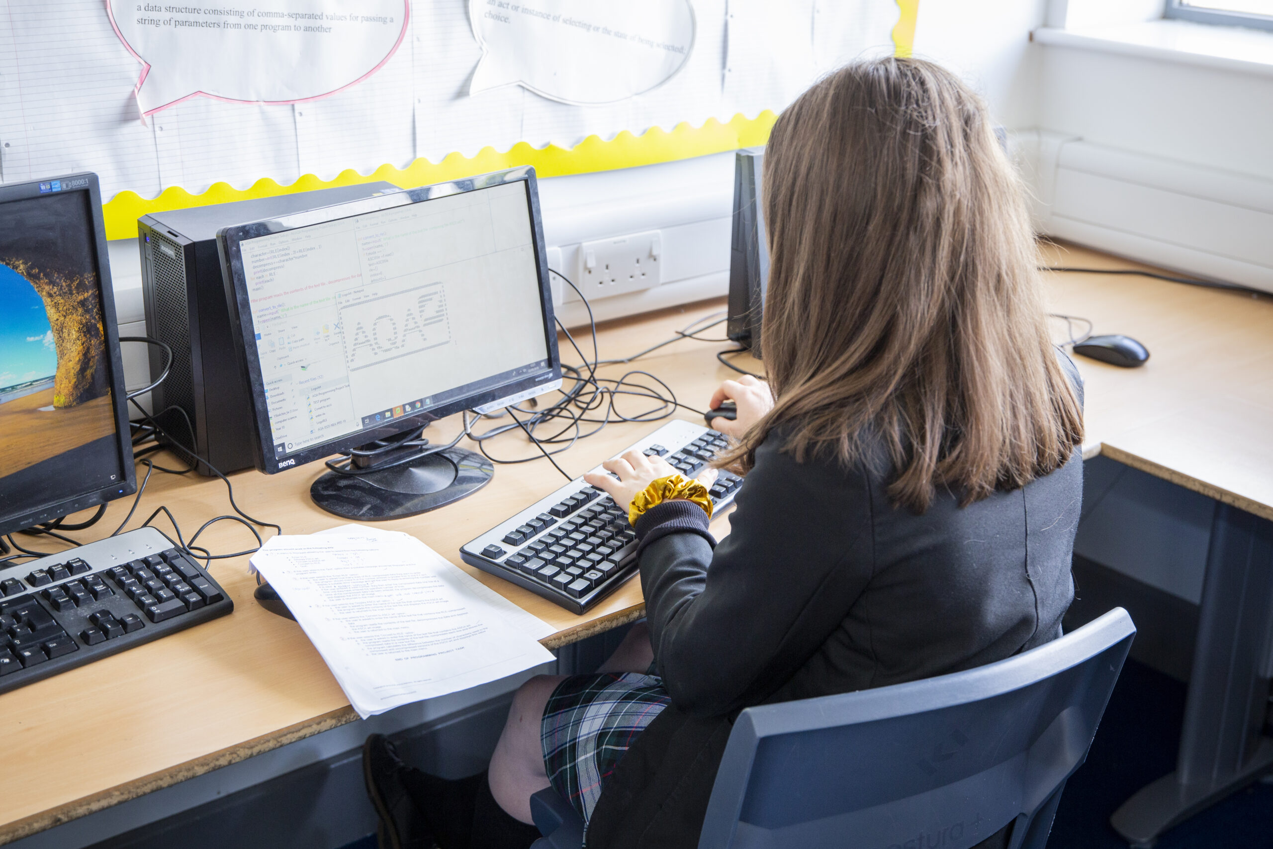 a teenage girl does coding during a computer science lesson.