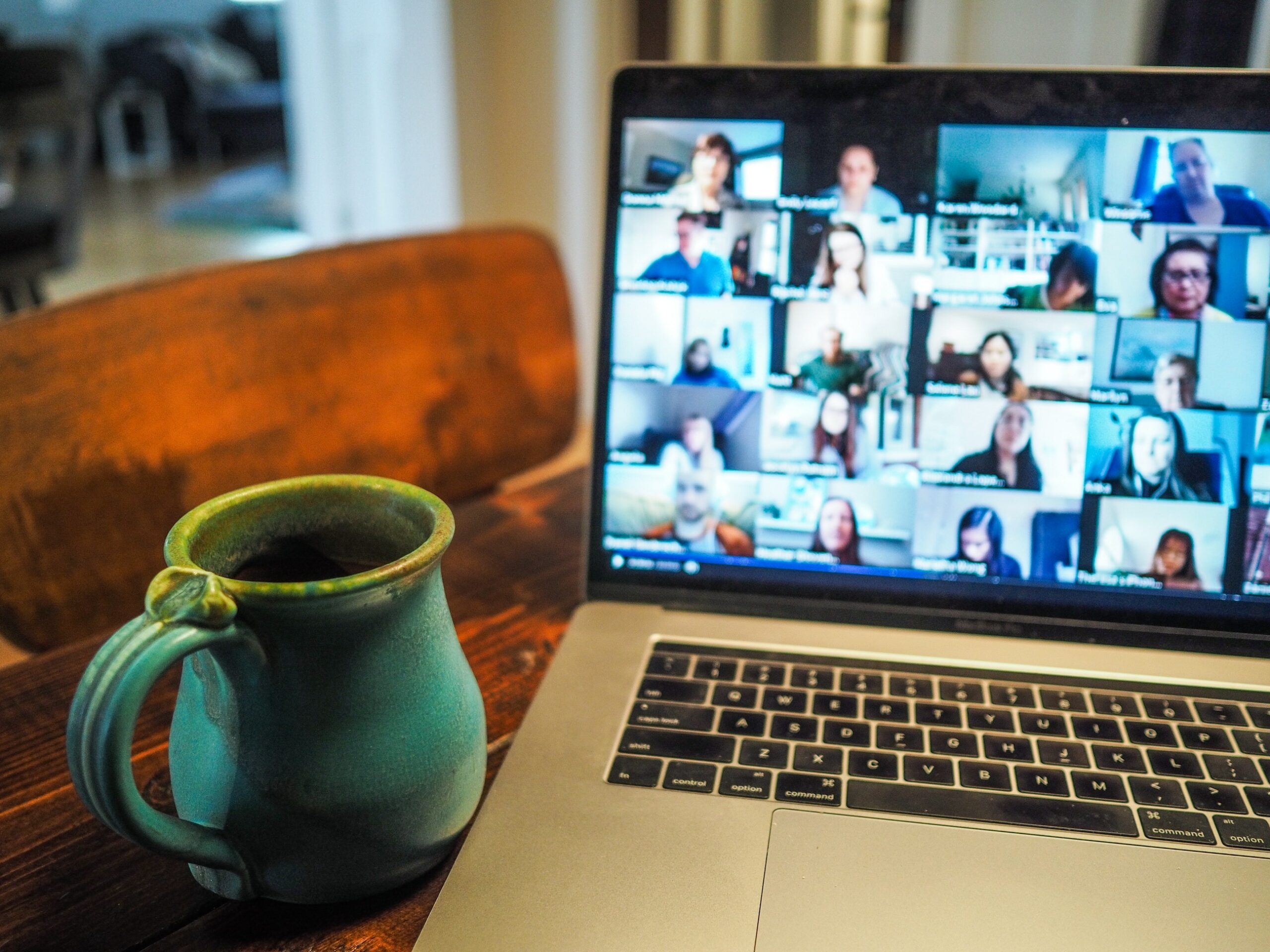 An earthenware mug next to a laptop showing a grid of video call participants.