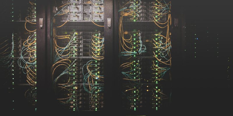 Stacks of server hardware behind metal fencing in a data centre.