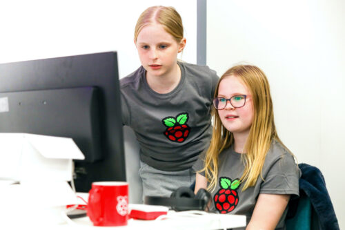 Two girls code together at a computer.