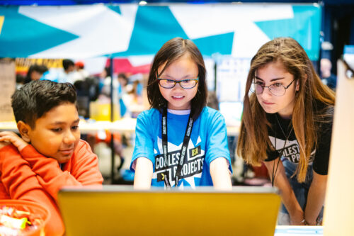 A young coder shows off her tech project for Coolest Projects to two other young tech creators.