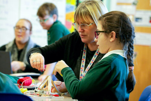 A computing teacher and a learner do physical computing in the primary school classroom.