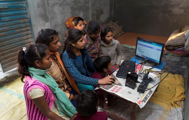 In rural India, a group of girls cluster around a computer.