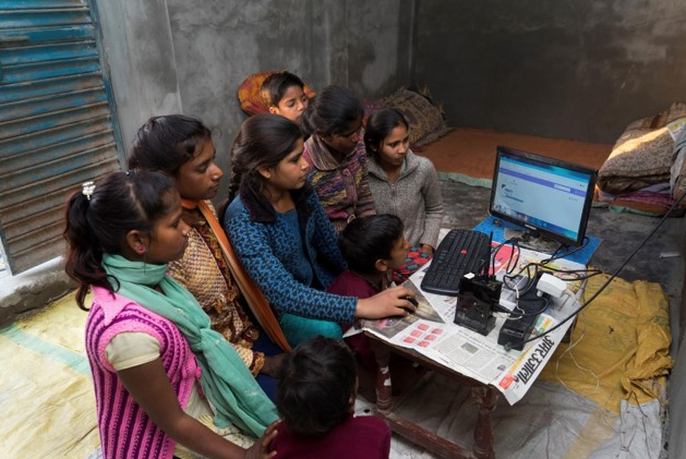 In rural India, a group of children cluster around a computer.