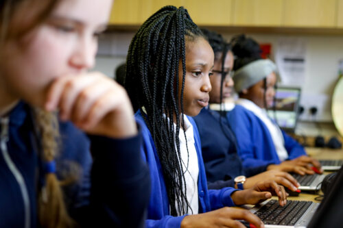 In a computing classroom, two girls concentrate on their programming task.