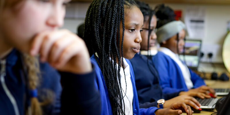 In a computing classroom, two girls concentrate on their programming task.