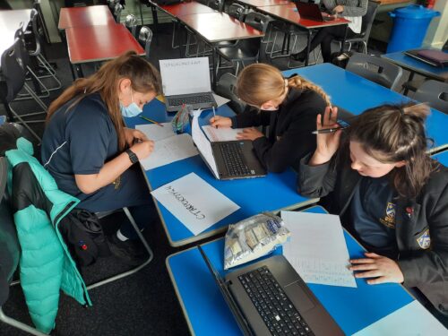 Girls do a cybersecurity activity at a school club.