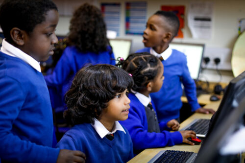Young learners at computers in a classroom.