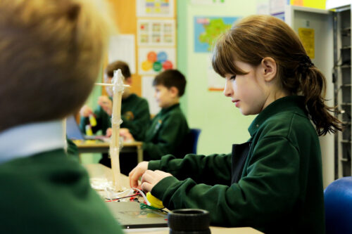 A girl does physical computing in a classroom.