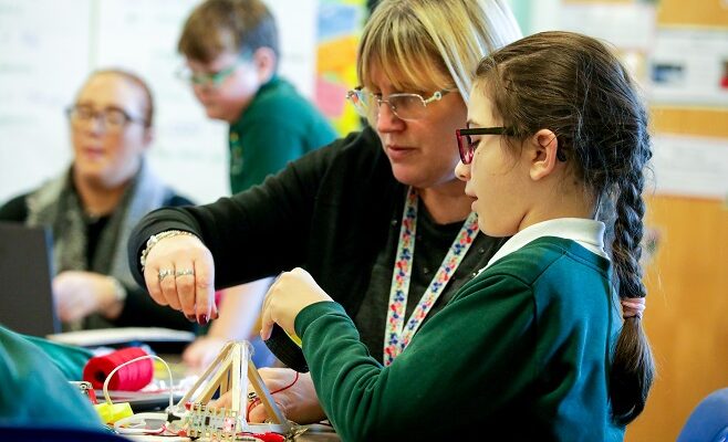 A computing teacher and a learner do physical computing in the primary school classroom.
