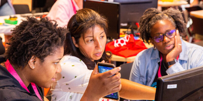 Three computer science educators discuss something at a screen.