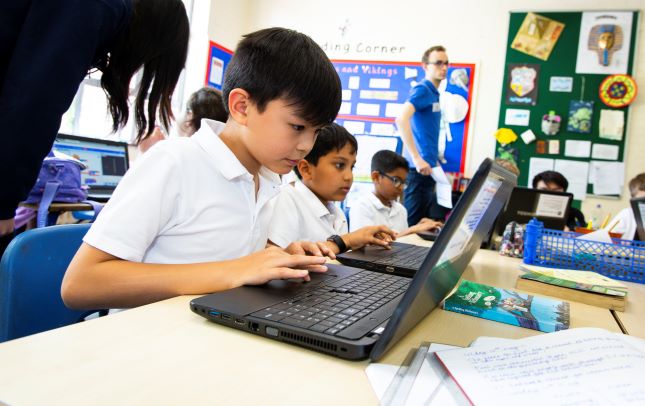 A group of learners using laptops at a computing session.  