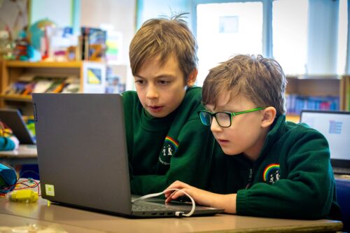 Two learners sharing a laptop in a coding session.