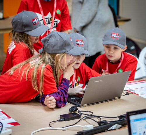 Four young people working together on a tech project.