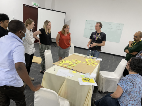 Workshop attendees stand around a table.